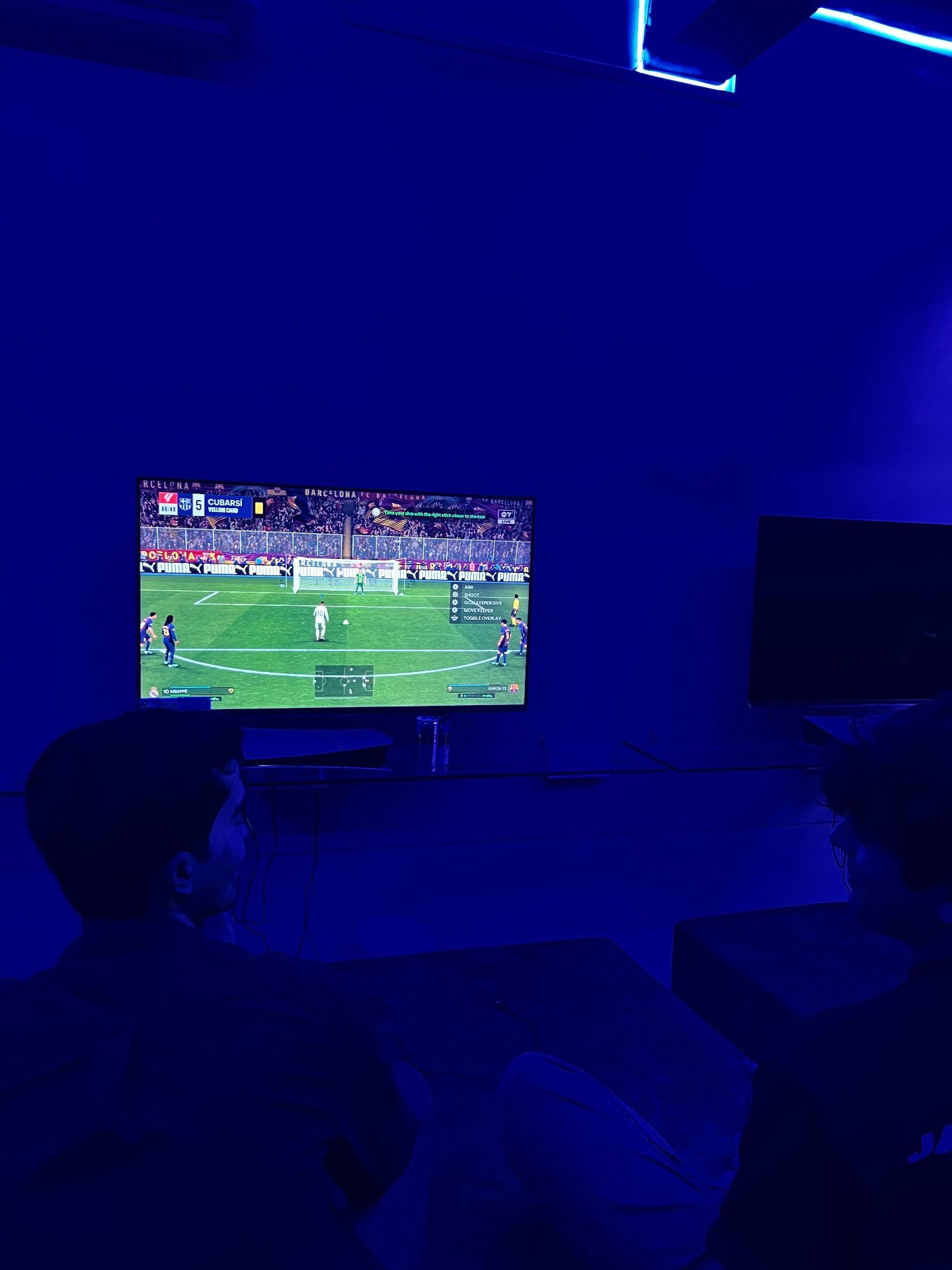 Friends gaming on PS5 in blue neon lounge