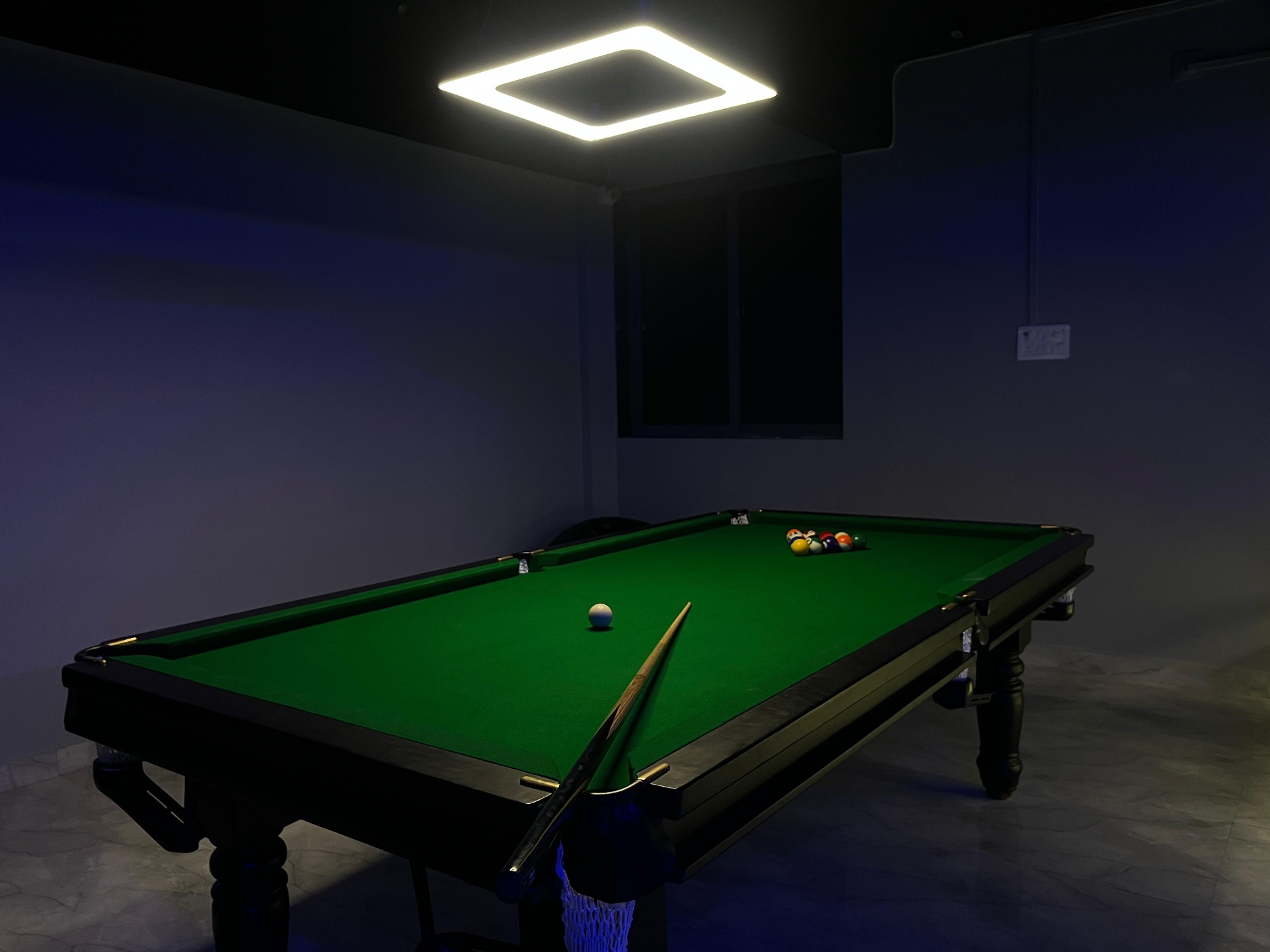 Pool table racked and ready under moody lighting